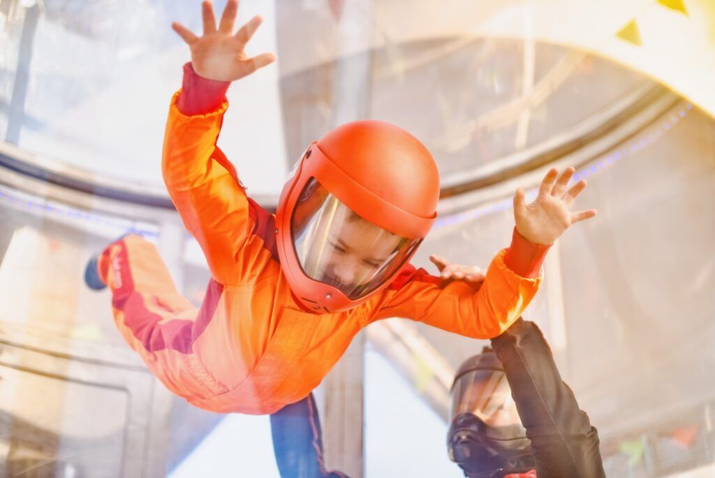 Boy flying in wind tunnel with instructor.